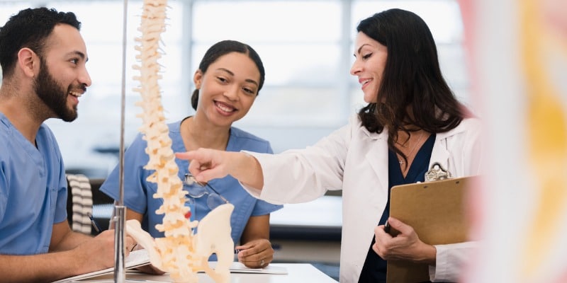 Professor pointing out vertebrae in spine to students - 5 Ways a Career College can Jumpstart Your Success